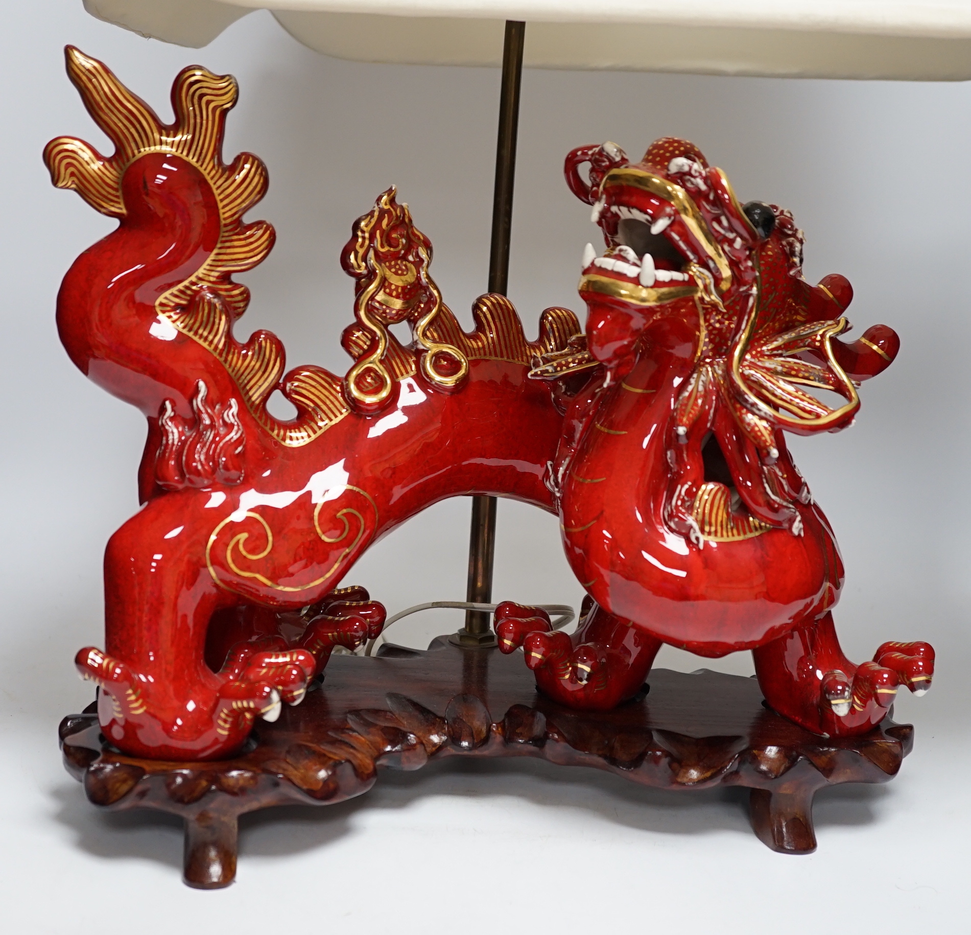 A modern Chinese red and gilt glazed ceramic 'dragon' table lamp on carved wood stand with shade, total height 68cm